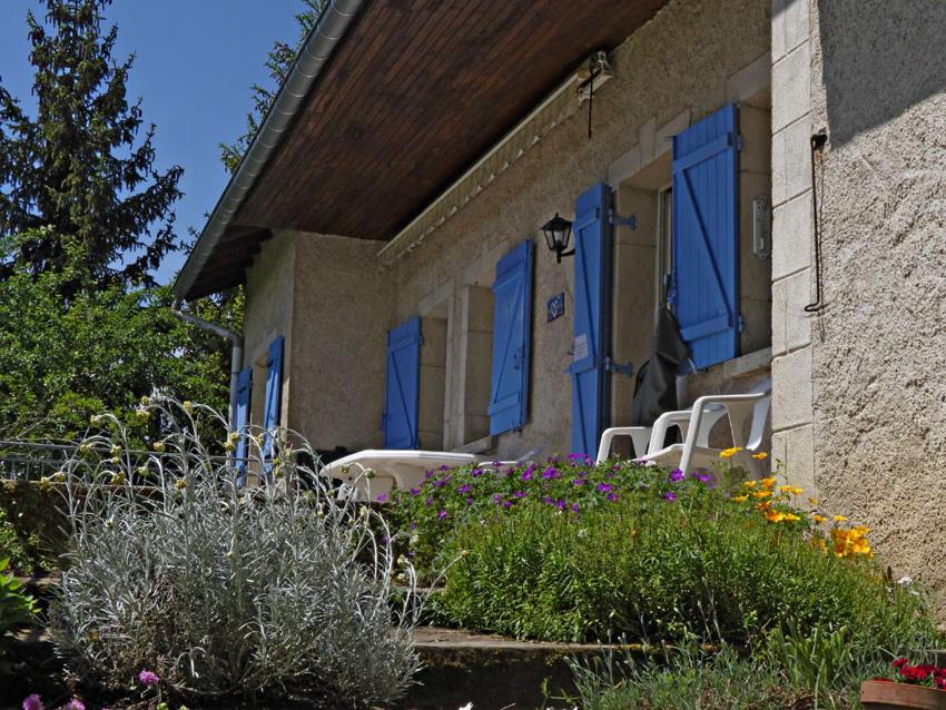 ein Haus mit blauen Fenstern, Stühlen und Blumen in der Unterkunft le lansquenet in Rorbach-lès-Dieuze