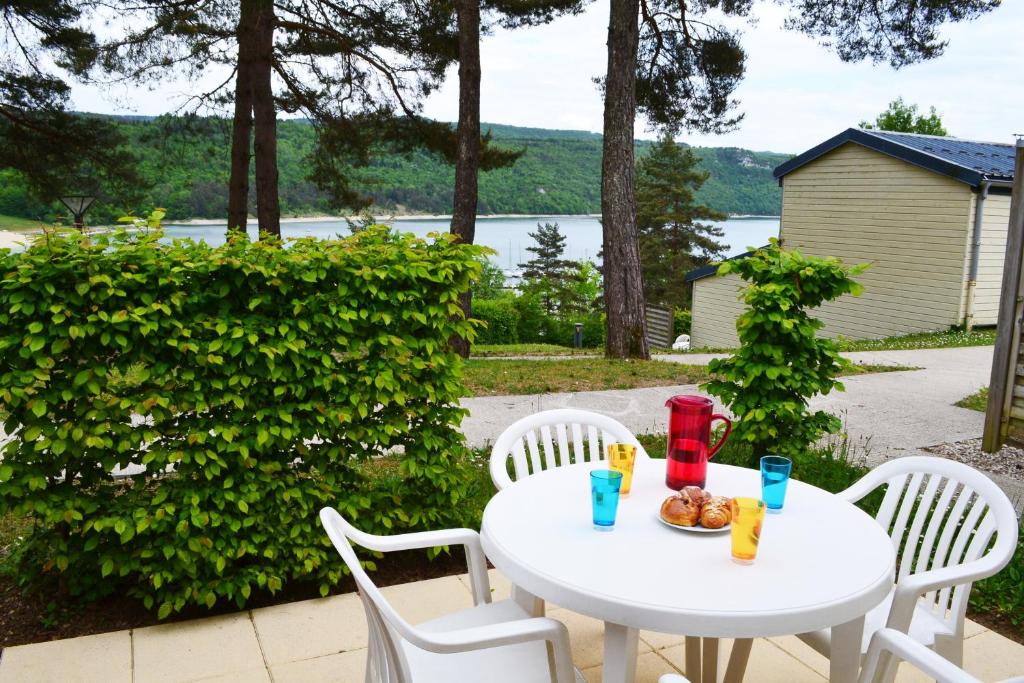 une table et des chaises blanches avec une assiette de nourriture dans l'établissement VVF Jura Lac de Vouglans, à Maisod