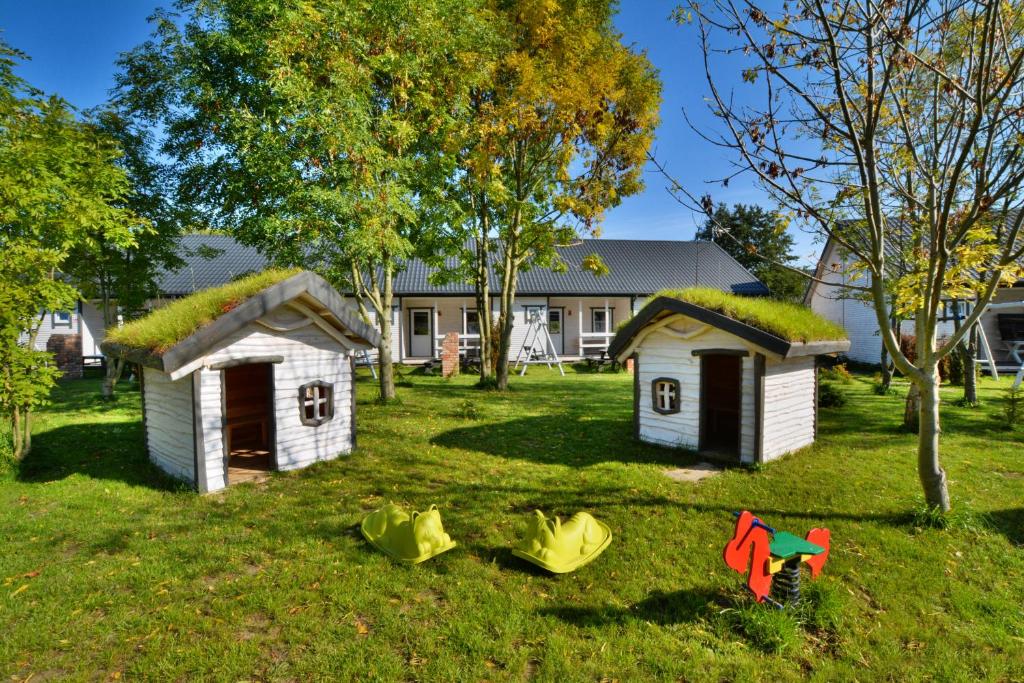 two small houses with grass roofs on a yard at Rodzinne Rusinowo in Rusinowo