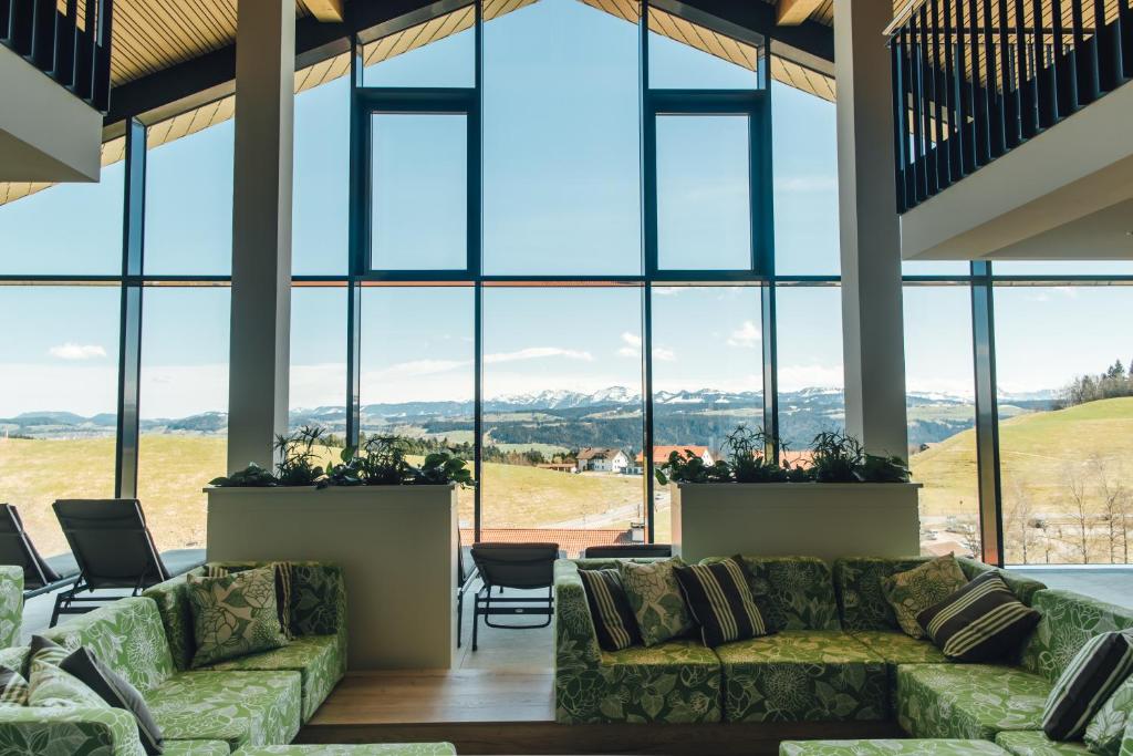 una sala de estar con sofás y ventanas grandes. en Hotel Edita, en Scheidegg