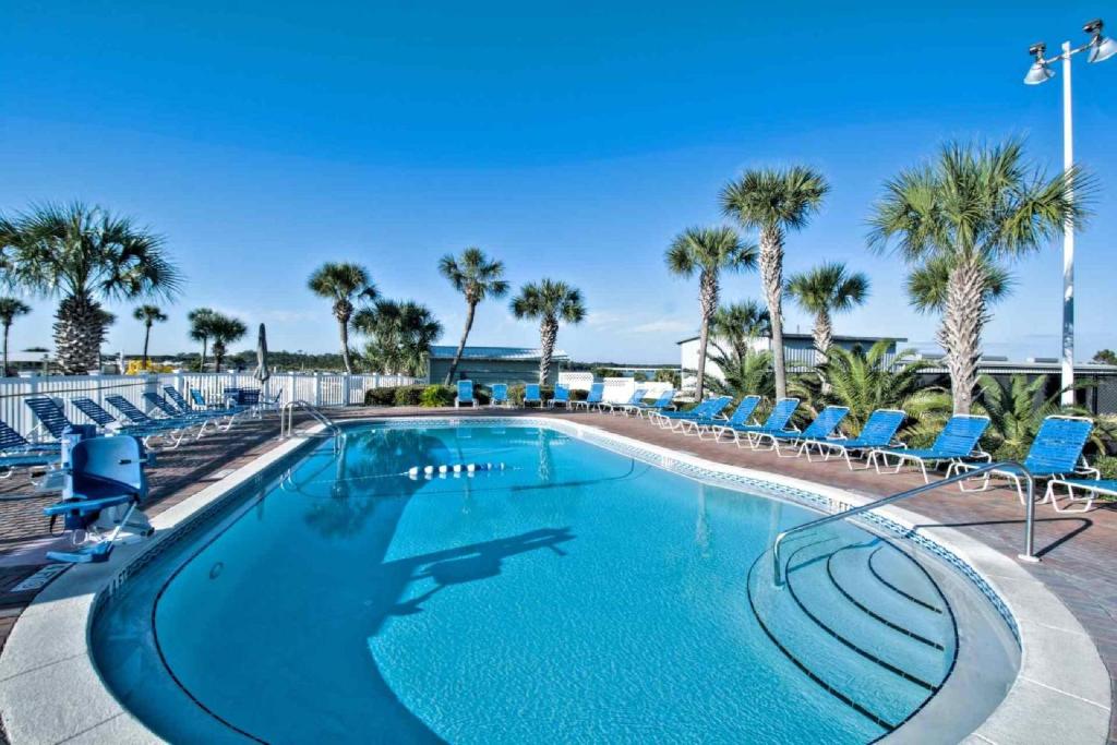 a large swimming pool with chairs and palm trees at Pinnacle Port C1-302 in Carillon Beach