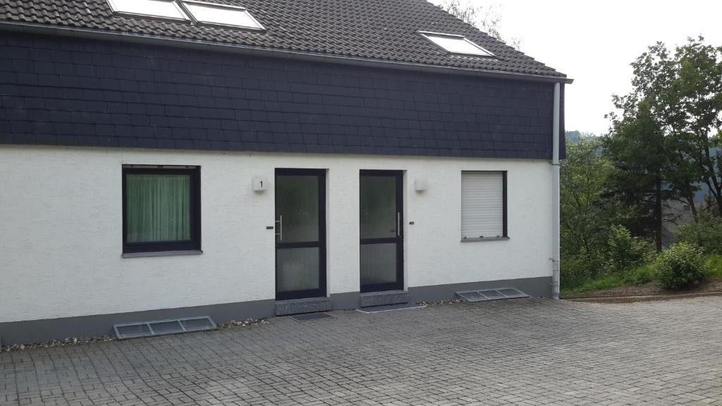 a white house with a black roof and two doors at Niedersfeld Polzweg in Winterberg