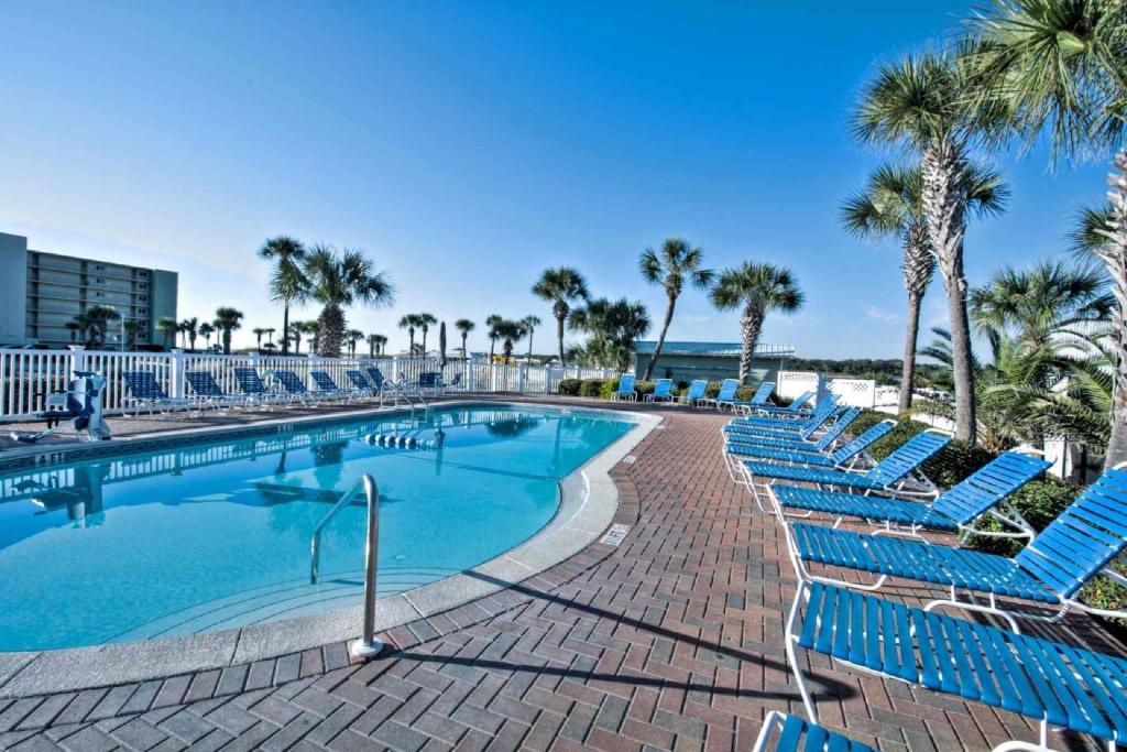 a swimming pool with blue chairs and palm trees at Pinnacle Port B3-307 in Carillon Beach