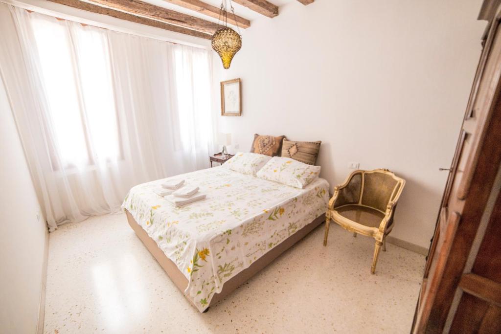 ein Schlafzimmer mit einem Bett und einem Stuhl in der Unterkunft Ca' Drio San Marco in Venedig