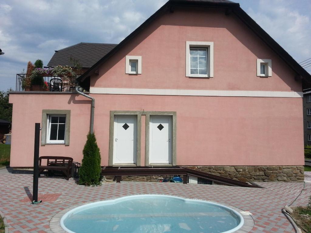 una casa rosa con una piscina frente a ella en apartmány Gingo, en Vrbno pod Pradědem