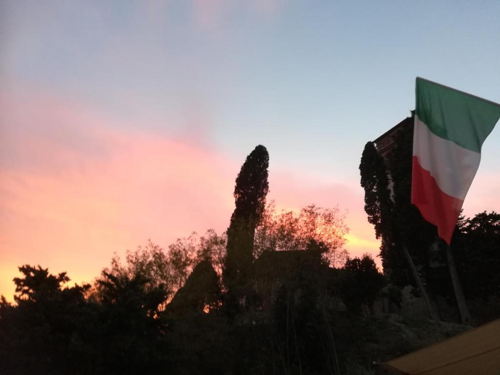 uma bandeira arvorando em frente a um pôr-do-sol em Borgo della Rocca em Montemurlo