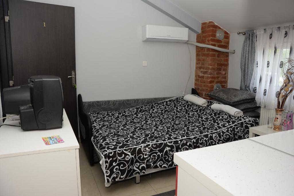 een kleine kamer met een bed met zwart-witte lakens bij House La Strada in Negotino