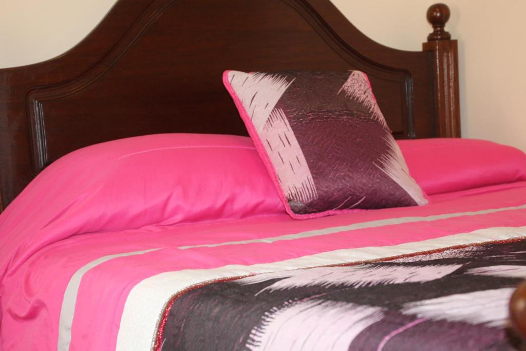 uma cama rosa com uma almofada preta e rosa em Salvador Beach House II na Nazaré