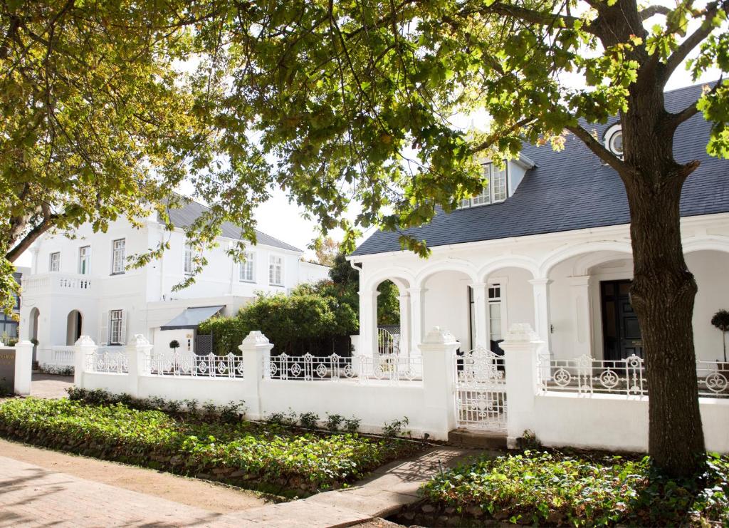 a white house with a white fence and a tree at River Manor Boutique Hotel by The Living Journey Collection in Stellenbosch