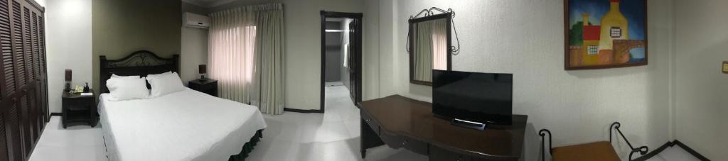1 dormitorio con 1 cama blanca y TV en Habitación Independiente en Santa Cruz de La Sierra en Hotel Casablanca, en Santa Cruz de la Sierra