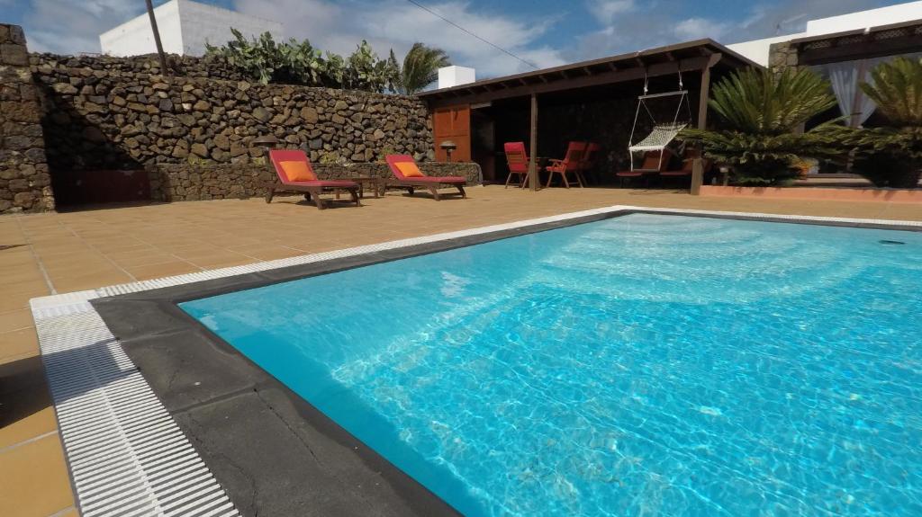a large blue swimming pool next to a house at Villa la petite in Guatiza
