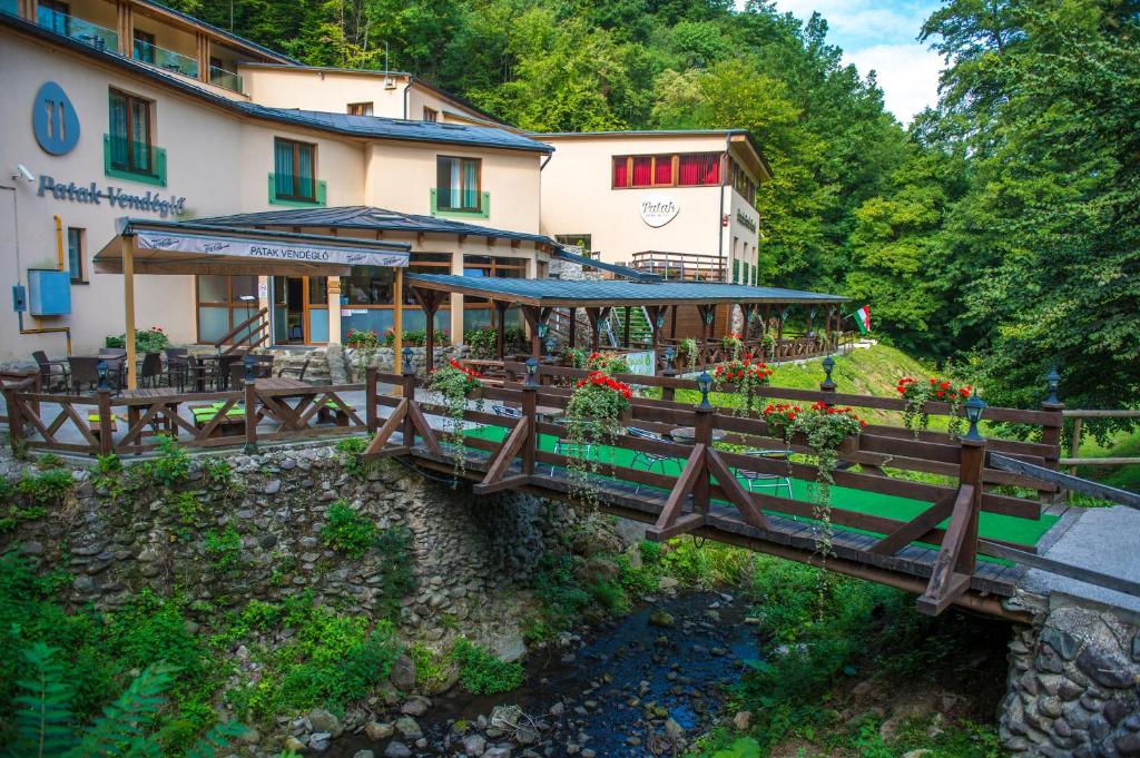 eine Brücke über einen Fluss vor einem Gebäude in der Unterkunft Patak Park Hotel Visegrád in Visegrád