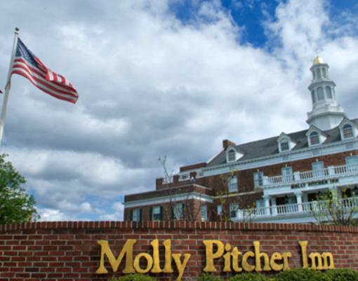 a large building with an american flag and a brick wall at Molly Pitcher Inn in Red Bank