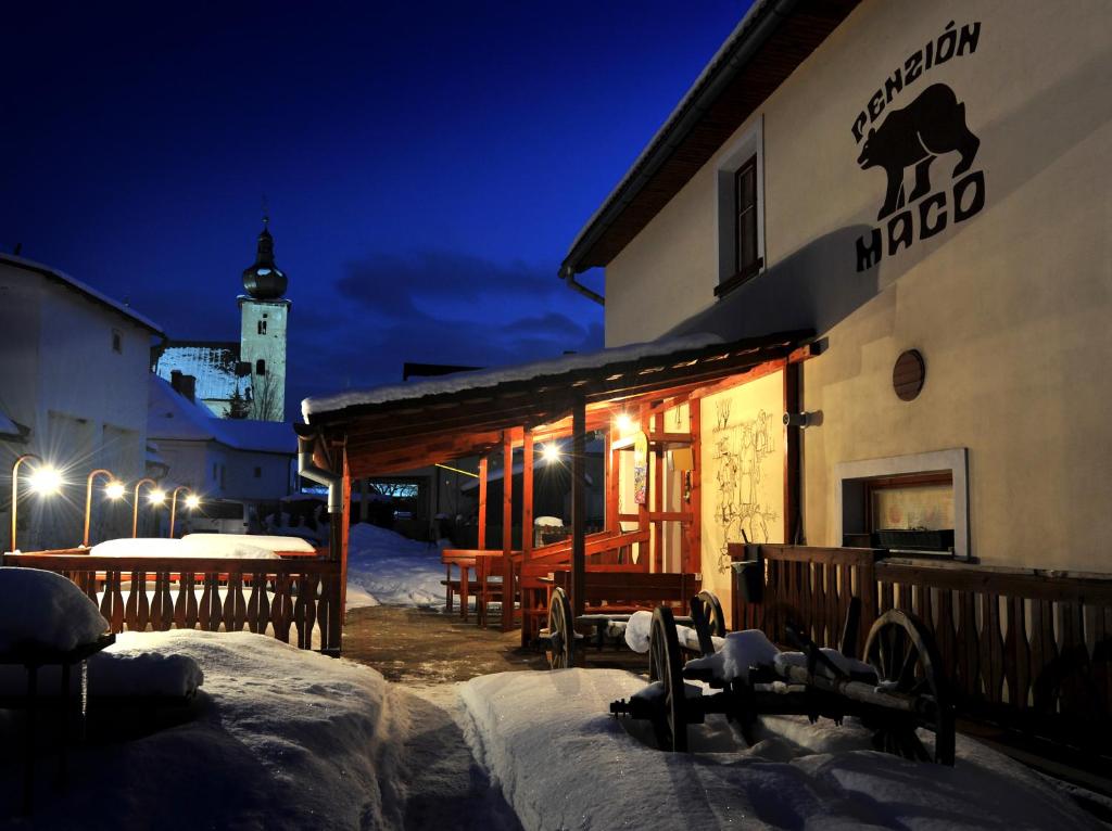 a building with a sign on the side of it at night at Penzion Maco in Liptovský Ján