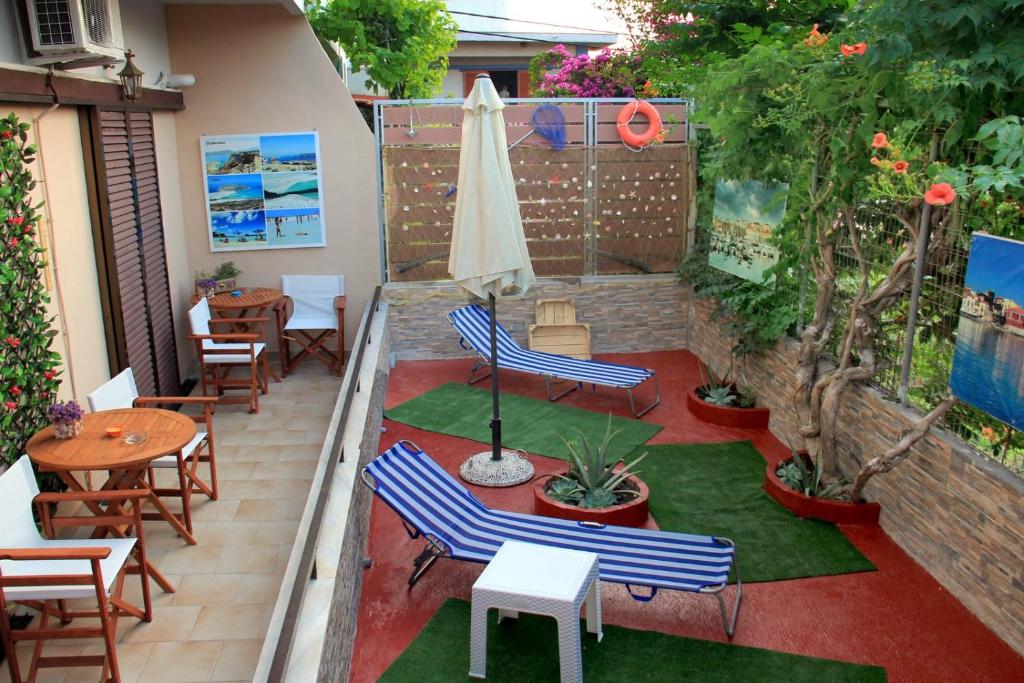 un patio con sillas, mesas y una sombrilla en Your Home en Kato Daratso
