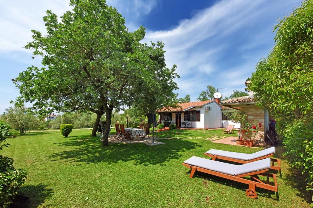 a yard with two lounge chairs and a house at Holiday Home Sergo in Poreč