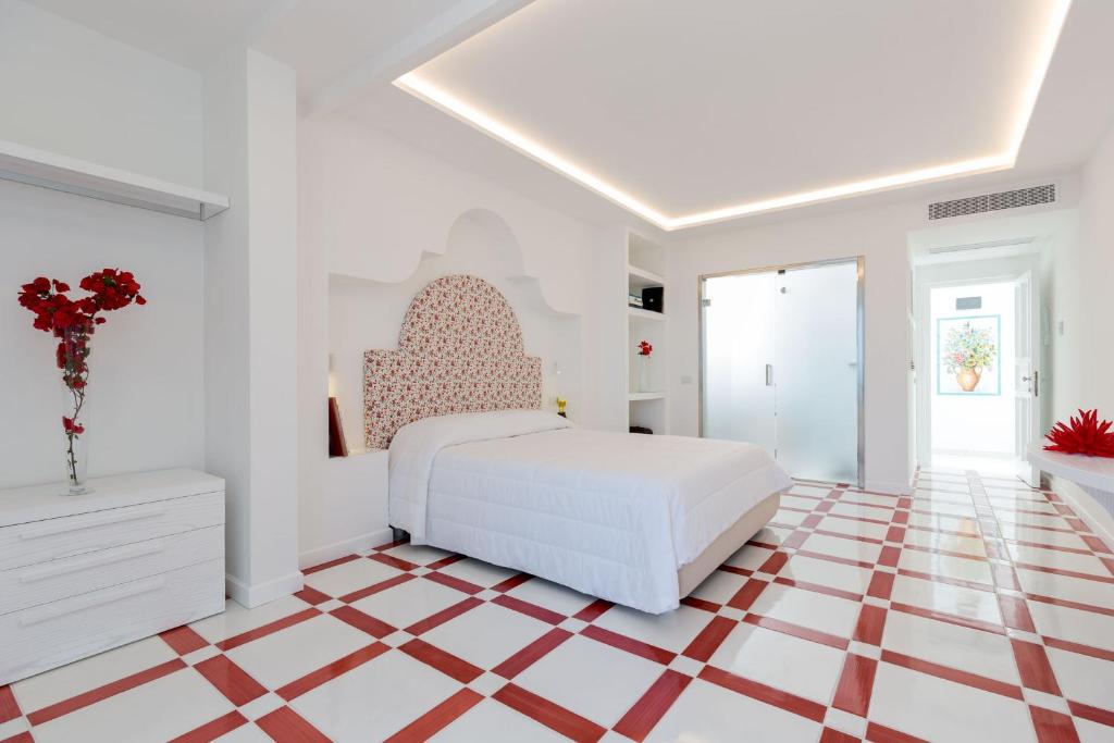 a white bedroom with a bed and a checkered floor at Quattro Passi Relais in Nerano