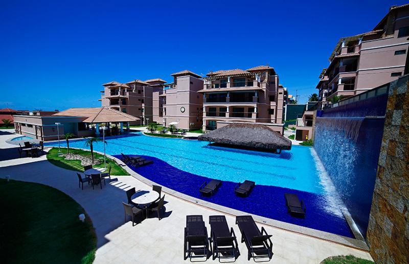 einen großen Pool mit Liegestühlen und Gebäuden in der Unterkunft Cobertura Duplex Beverly Hills in Aquiraz