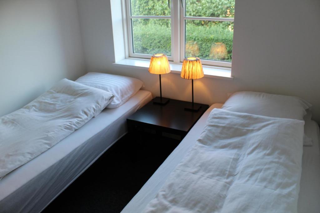 two beds in a room with two lamps on a table at Close But Quiet in Herlev