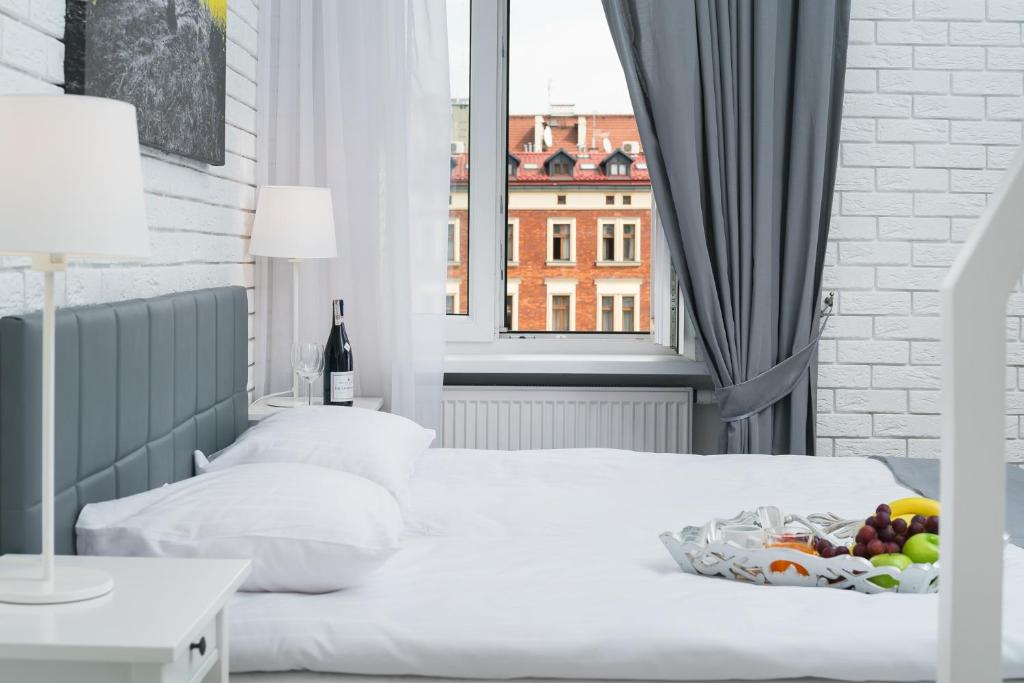 Low-angle bed view toward open window showcasing red-brick building facades across the street.