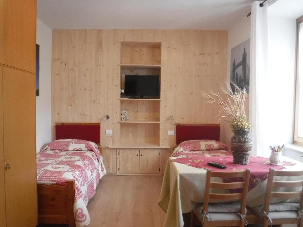 1 Schlafzimmer mit 2 Betten, einem Tisch und Stühlen in der Unterkunft Al Bait de Giò in Bormio