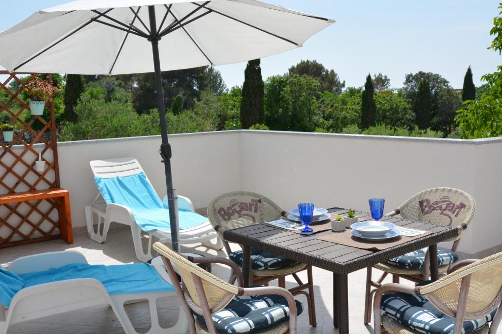 patio ze stołem, krzesłami i parasolem w obiekcie Apartments Relax Punat w mieście Punat