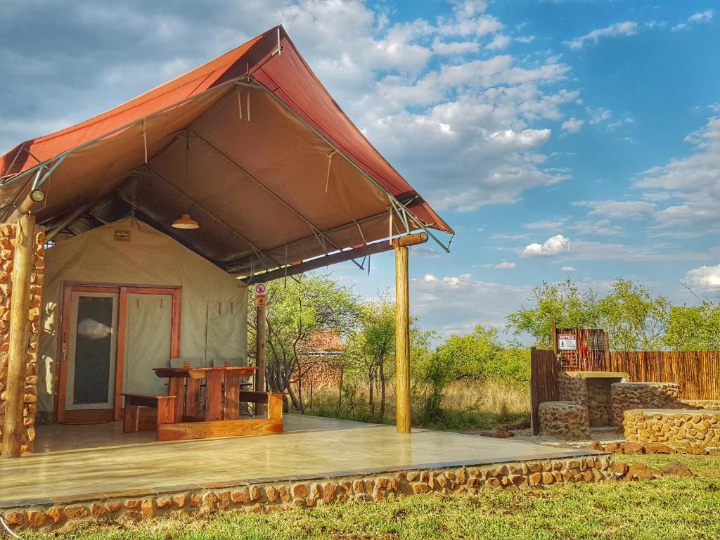 Casa pequeña con techo rojo y terraza de madera en OuKlip Game Lodge en Klipdrift