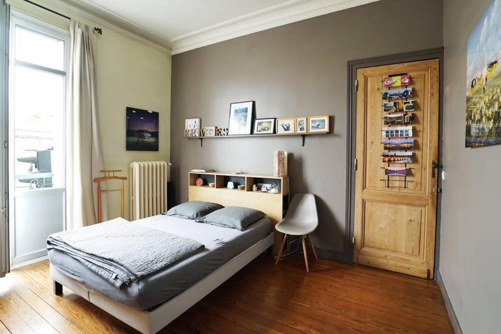 a bedroom with a bed and a door and a chair at Au Petit Bonheur in Talence