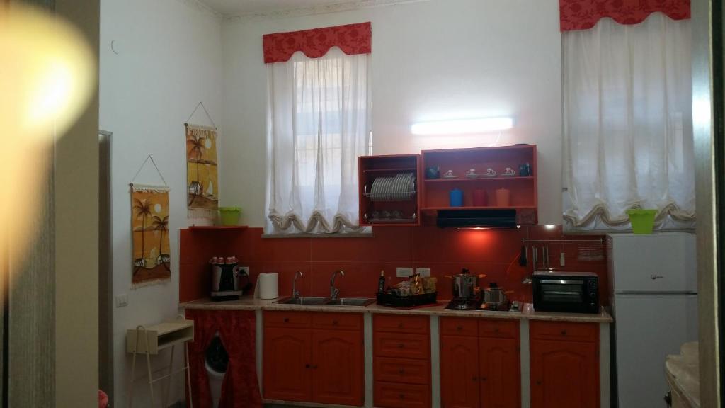 uma cozinha com armários vermelhos e um frigorífico branco em Casa Marta em Palermo
