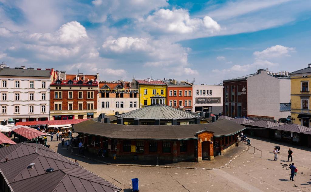 Circular market hall in sunny town square surrounded by colorful historic buildings and people.