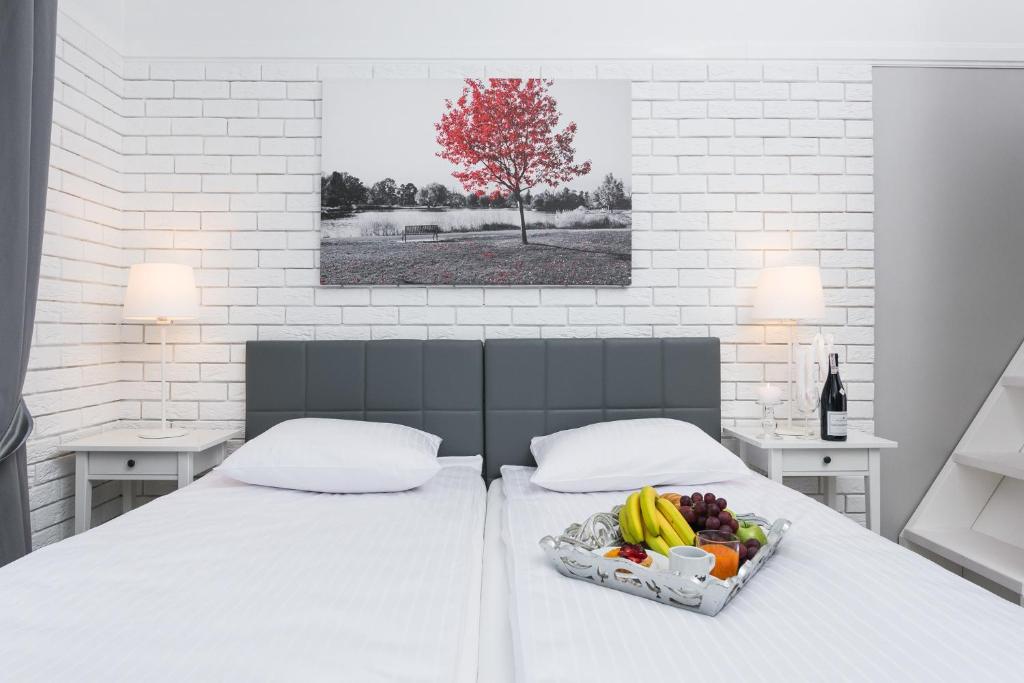 Twin beds with fruit tray, soft lighting and black-and-white tree artwork featuring red foliage.