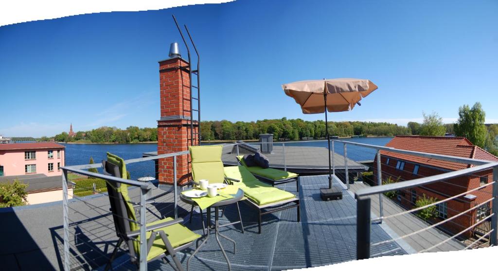 una terraza con sillas, una mesa y una sombrilla en "Über den Dächern" en Malchow