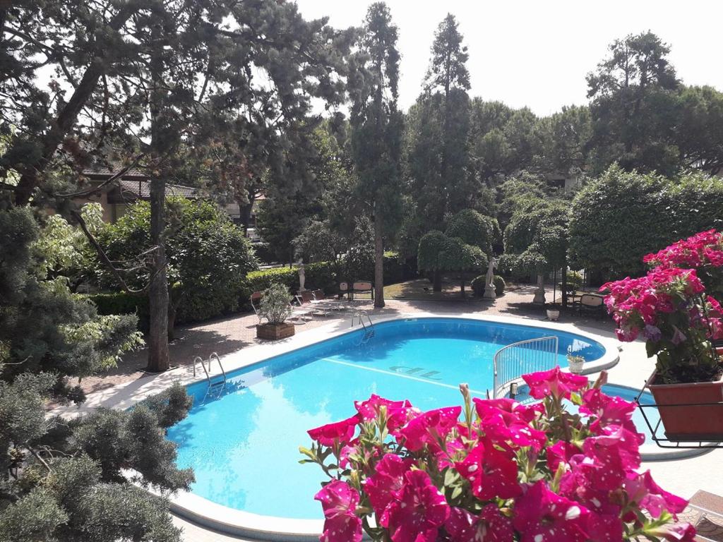a swimming pool in a garden with pink flowers at New Tiffany's Park in Lido di Jesolo