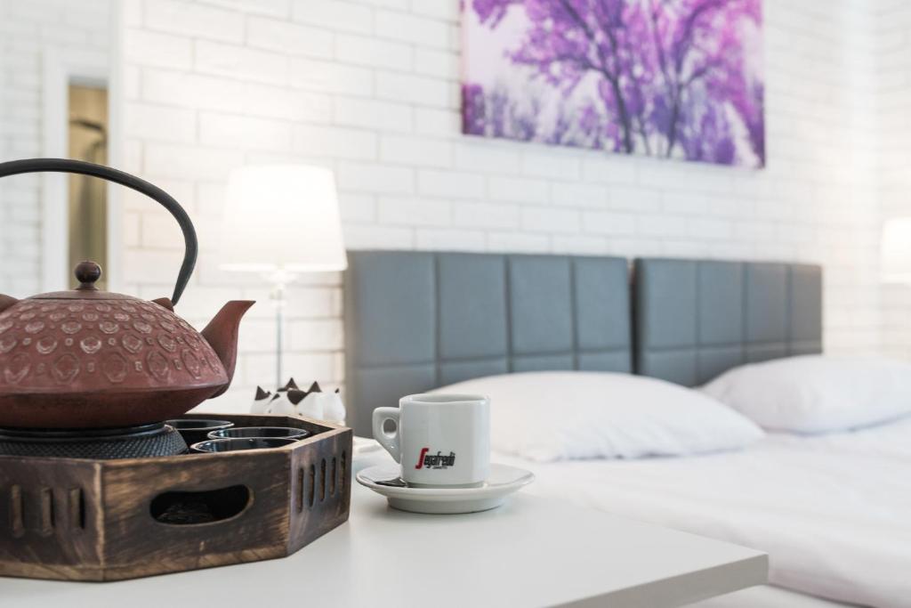 Cast iron teapot and espresso cup on wooden tray beside bed, soft lamp, purple artwork