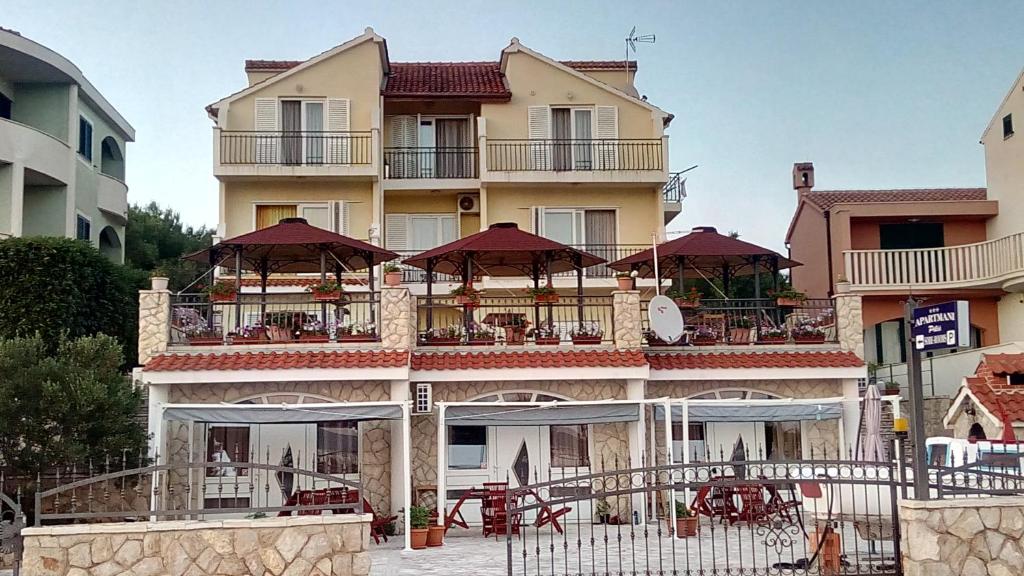 a large building with tables and umbrellas on it at Apartments Pilić in Šibenik