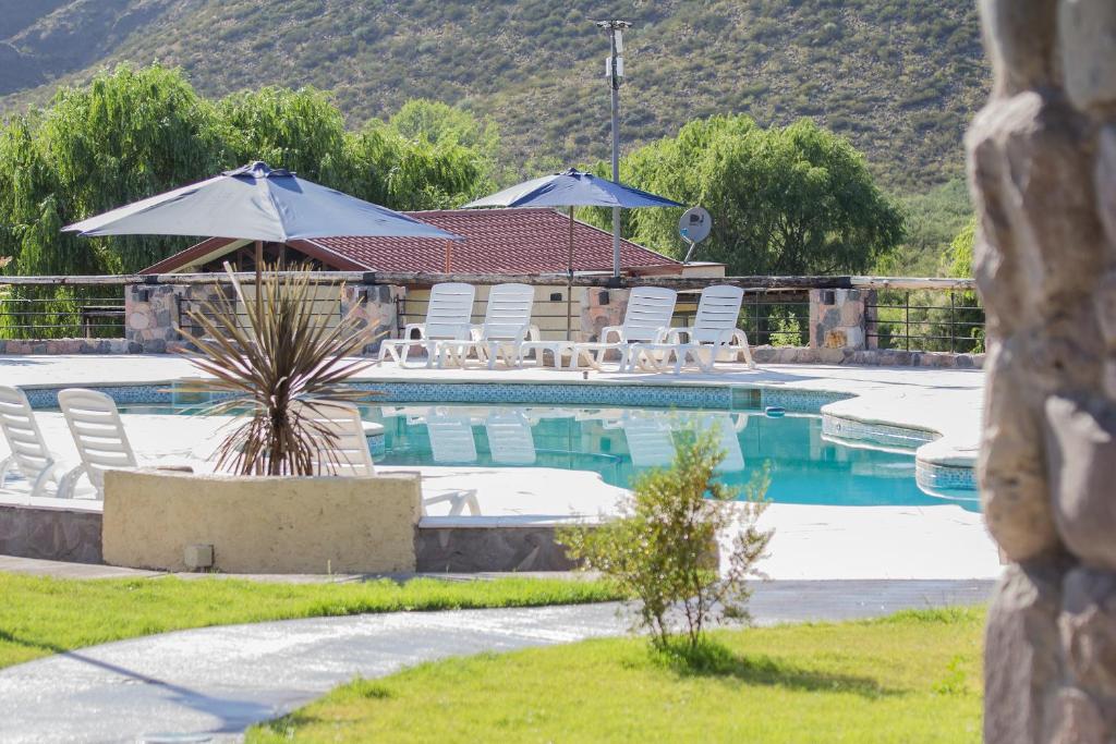 una piscina con sillas y sombrillas en un complejo en Los Chalecitos en Valle Grande