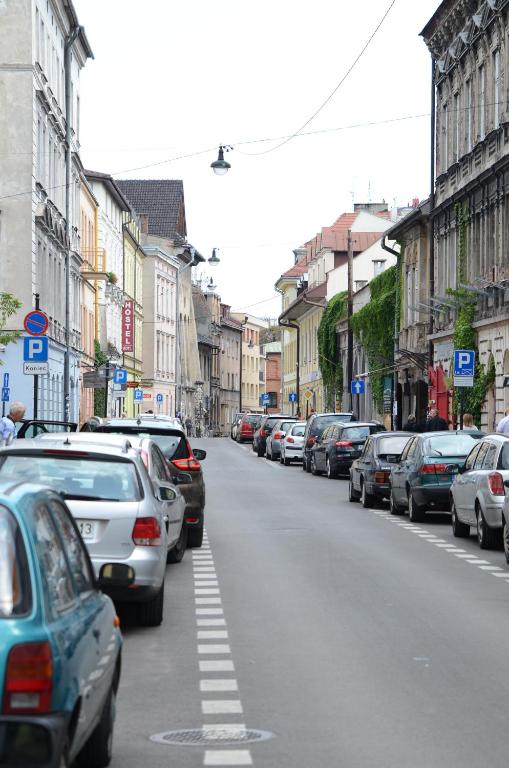 Quiet city street flanked by parked cars and older multi-story buildings, overcast sky.