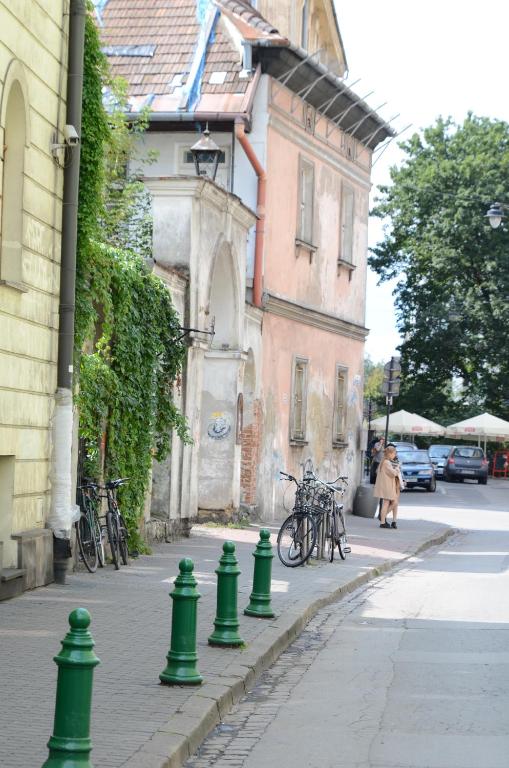 Narrow street with ivy-covered building, row of green bollards, parked bicycles, pedestrians in background