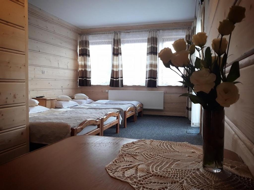 ザコパネにあるWilla Perełkaのベッド4台、テーブルに花瓶