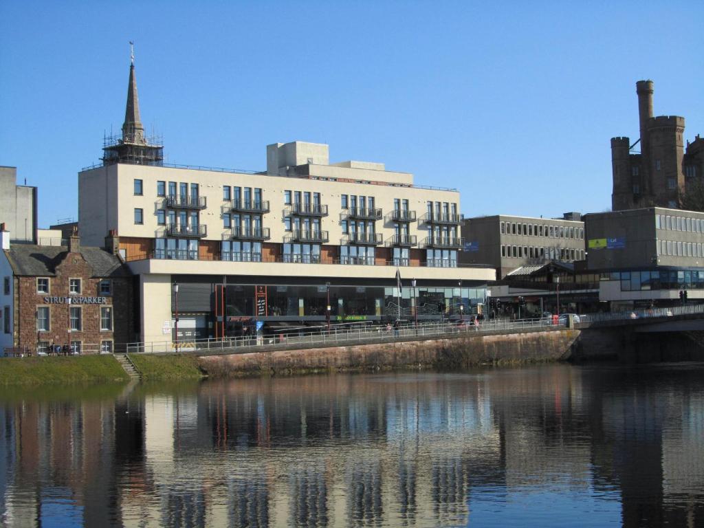 a large building next to a body of water at Bridge Street Apartments in Inverness