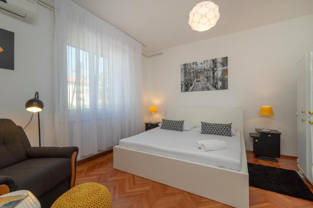a white bedroom with a bed and a couch at Apartman Karmen in Trogir