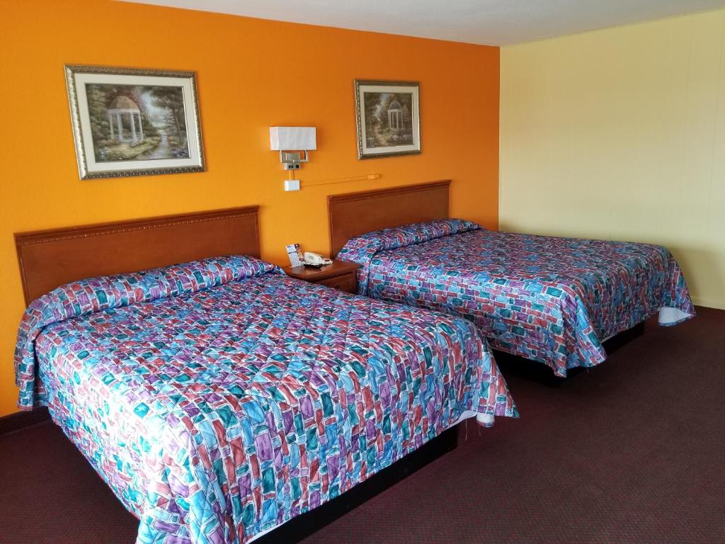 two beds in a hotel room with orange walls at Eldon Inn in Eldon