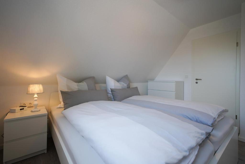 uma grande cama branca num quarto com um candeeiro em Dünenhus Borkum em Borkum