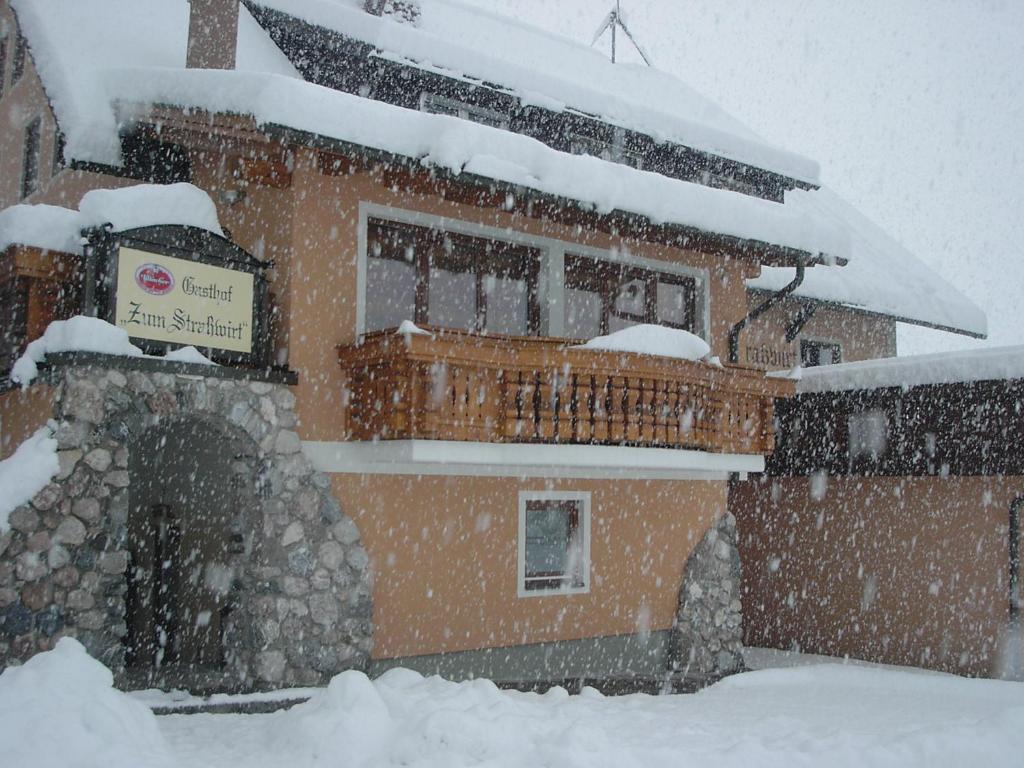 un edificio cubierto de nieve con un cartel. en Hotel-Gasthof Strasswirt, en Tröpolach