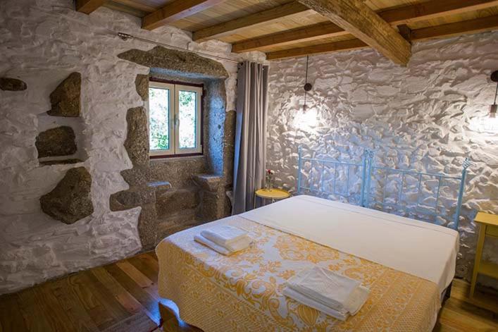 a bedroom with a bed in a stone wall at Casa da Assudra in Vila Verde
