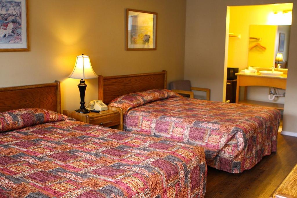 a hotel room with two beds and a lamp at San Luis Inn and Suites in San Luis Obispo