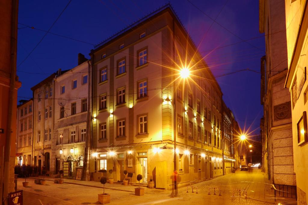 an old building with lights on a street at night at Vintage Boutique Hotel in Lviv