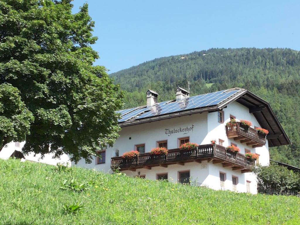 a building on a hill with flower boxes on it at Gruppenhaus Thalackerhof in Brunico