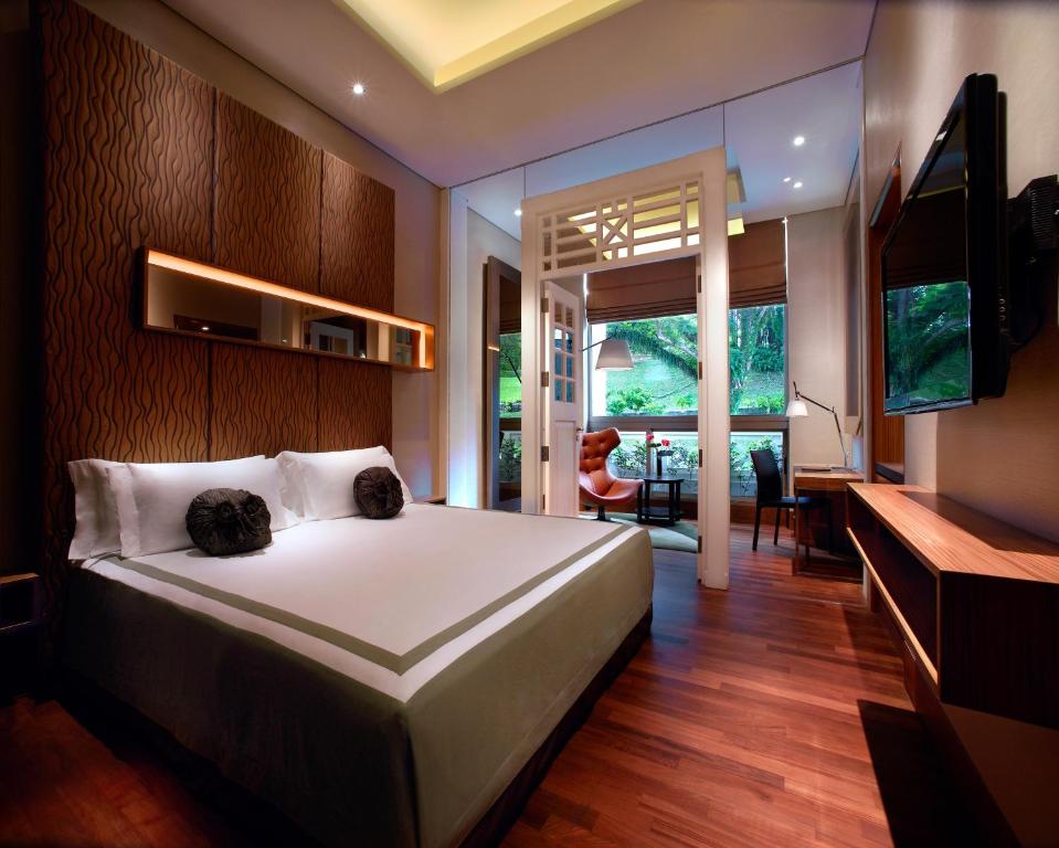 a bedroom with a large white bed and a desk at Hotel Fort Canning in Singapore