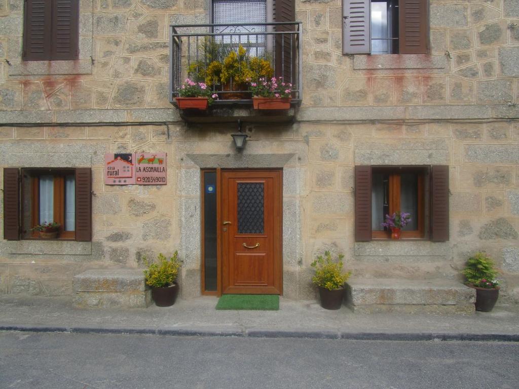 un edificio con puerta de madera y 2 ventanas en Holiday Home La Asomailla, en Hoyos del Espino